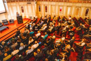 circa 100 Personen sitzen in Saal